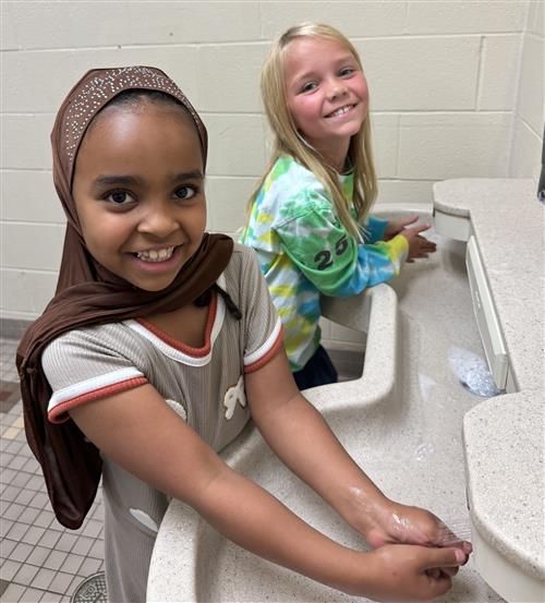 Two girls washing their hands and smiling